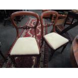 A set of four William IV mahogany balloon back chairs with carved back rail over turned and