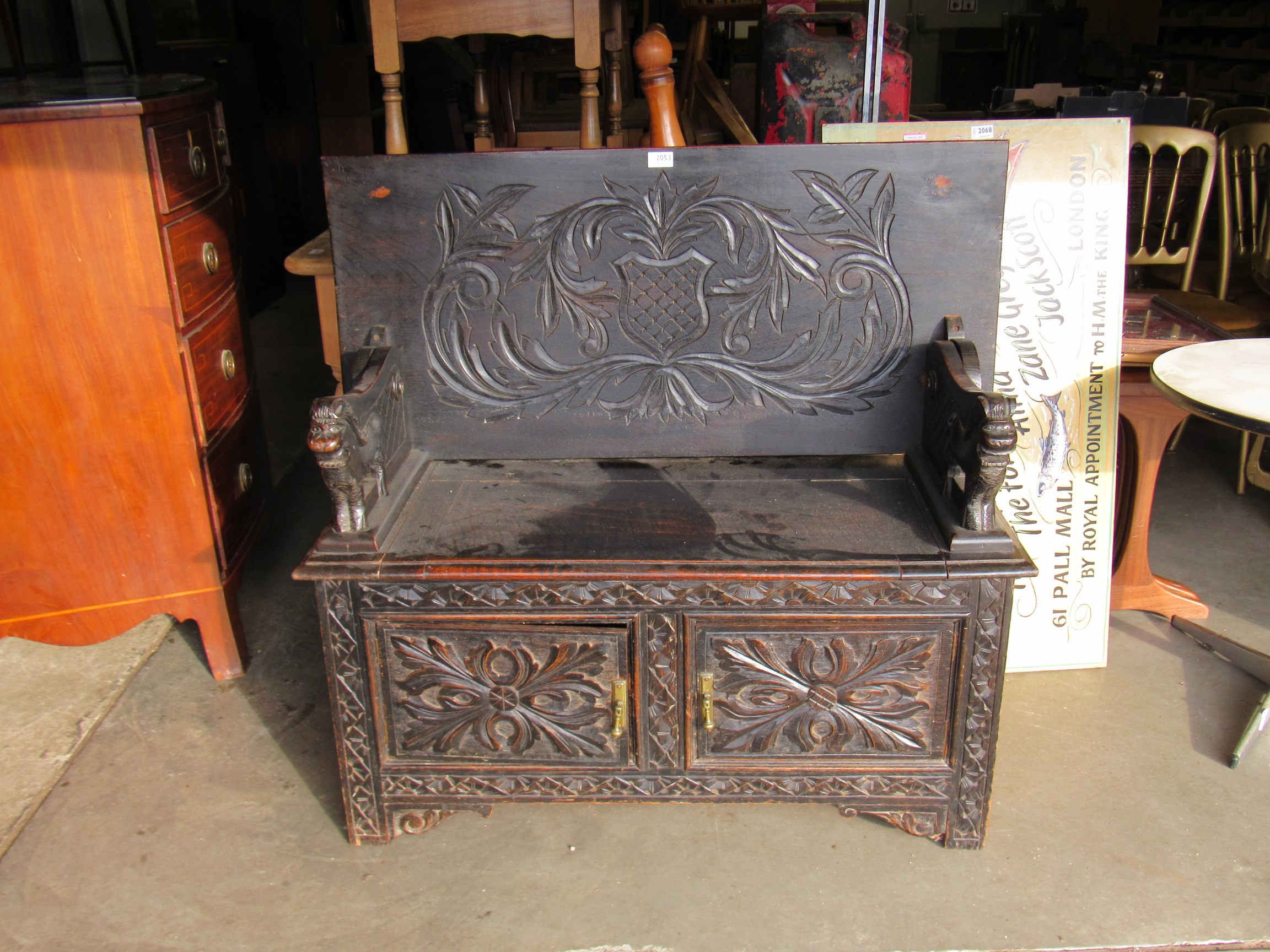 An Edwardian carved oak monks bench, with lift up seat,