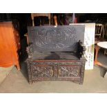 An Edwardian carved oak monks bench, with lift up seat,