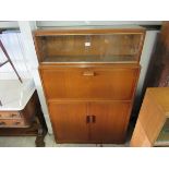 A 1950's mahogany bookcase with sliding glass top over a fall front and fitted interior,