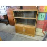 A 1940's/50's honey oak bookcase with two sections of sliding glass doors over two enclosed doors