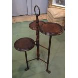 In the manner of Liberty & Co an Arts & Crafts mahogany three tier cake stand the brass ring handle