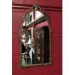 A gilt metal mirror of arched form with floral embellishment,