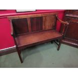 An early 20th Century slender oak settle with panel back,