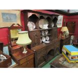 A Georgian style oak heavily carved dresser with shelved and cupboard back over three drawer,