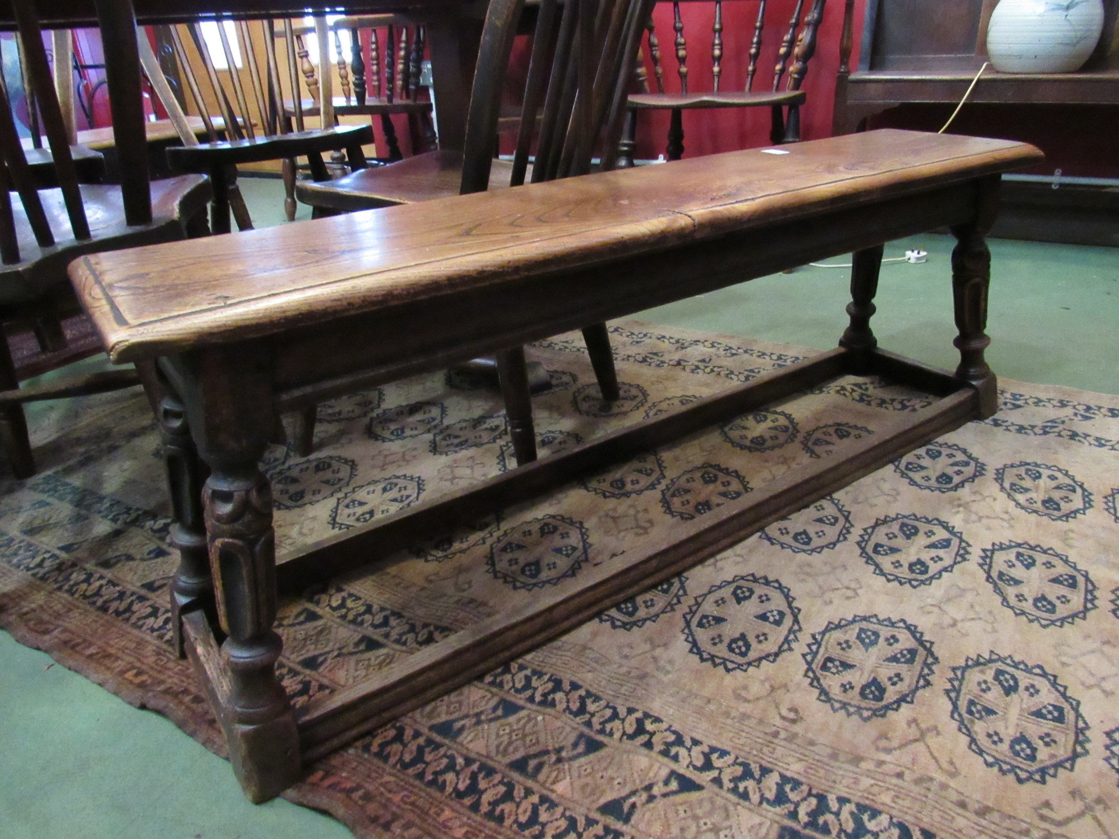 A 19th Century elm topped long stool/bench with carved and turned legs to H-stretcher,