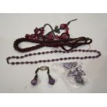 A collection of garnet beads and purple necklaces.