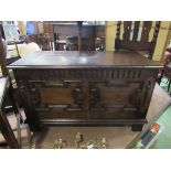 Circa 1920 an oak coffer the rising lid over a geometric moulded front on stile feet,