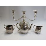 A silver plate three piece tea set and candlestick