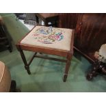 Circa 1920 an oak stool with needlepoint seat over turned legs joined by an "H" stretcher