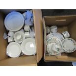 A box containing white and gilt tableware, including cups, saucers,