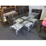 A metal framed glass top dining table and six wrought metal chairs