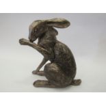 A resin bronze seated hare, preening,