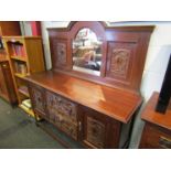 An oak sideboard with carved panel front and arched mirror back,