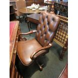 A button back leather swivel desk armchair with shepherd crrok shape arms and brass stud decoration