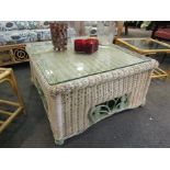 A wicker conservatory table with glass top,