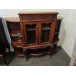 An Edwardian chiffonier base with glazed cupboard door, flanked by shelves,