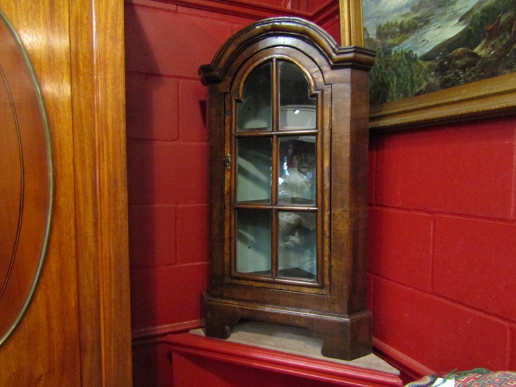 A George II style walnut dome top free standing corner cabinet the panel glazed door with key and