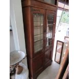 An Arts & Crafts oak four door bookcase with upper lead glazed doors and key