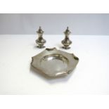 A pair of silver pepperettes, misshapen, and a Goldsmiths & Silversmiths dish,