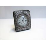 A silver embossed easel-back clock with Roman numerated dial, 11.