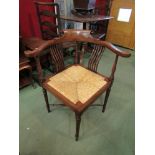 Circa 1840 an English fruitwood corner chair the scroll arms and back rest on square slatted and