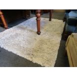 A beige shag pile style rug,