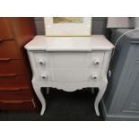 A modern white breakfront chest of two drawers raised on cabriole legs,