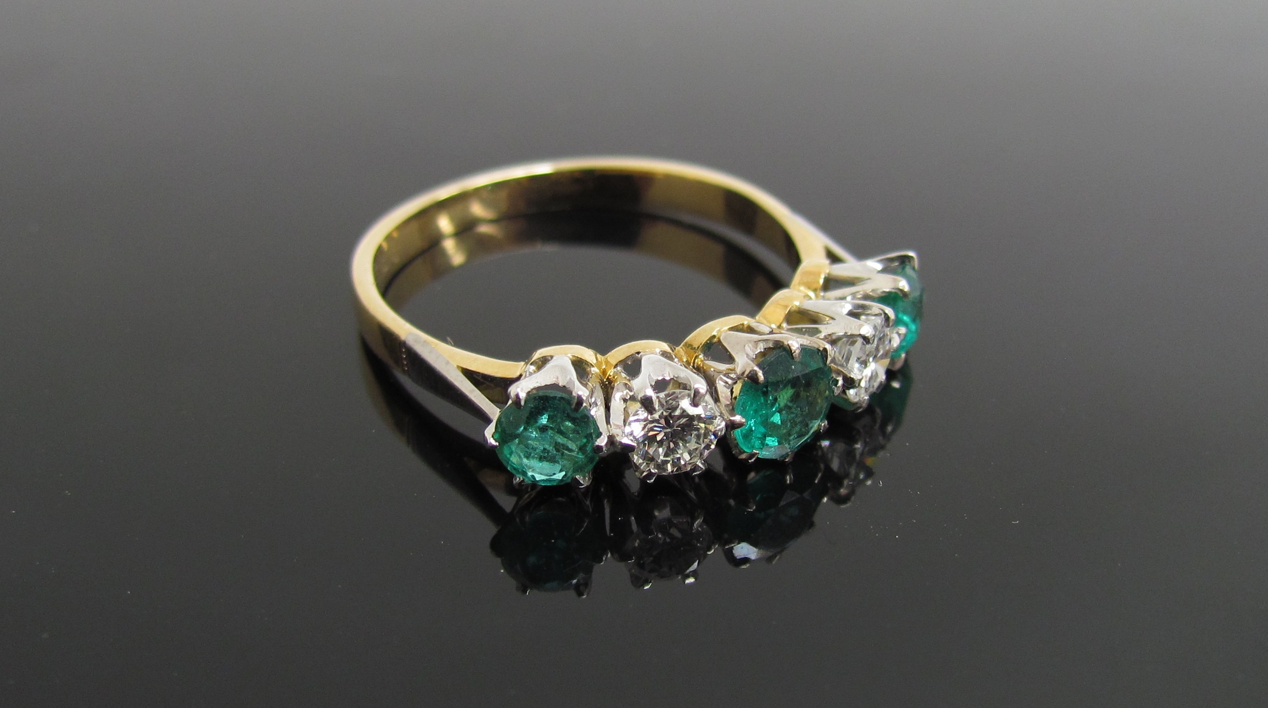 An emerald and diamond five stone ring, stamped 750/plat, .40ct diamond, .90ct emerald.