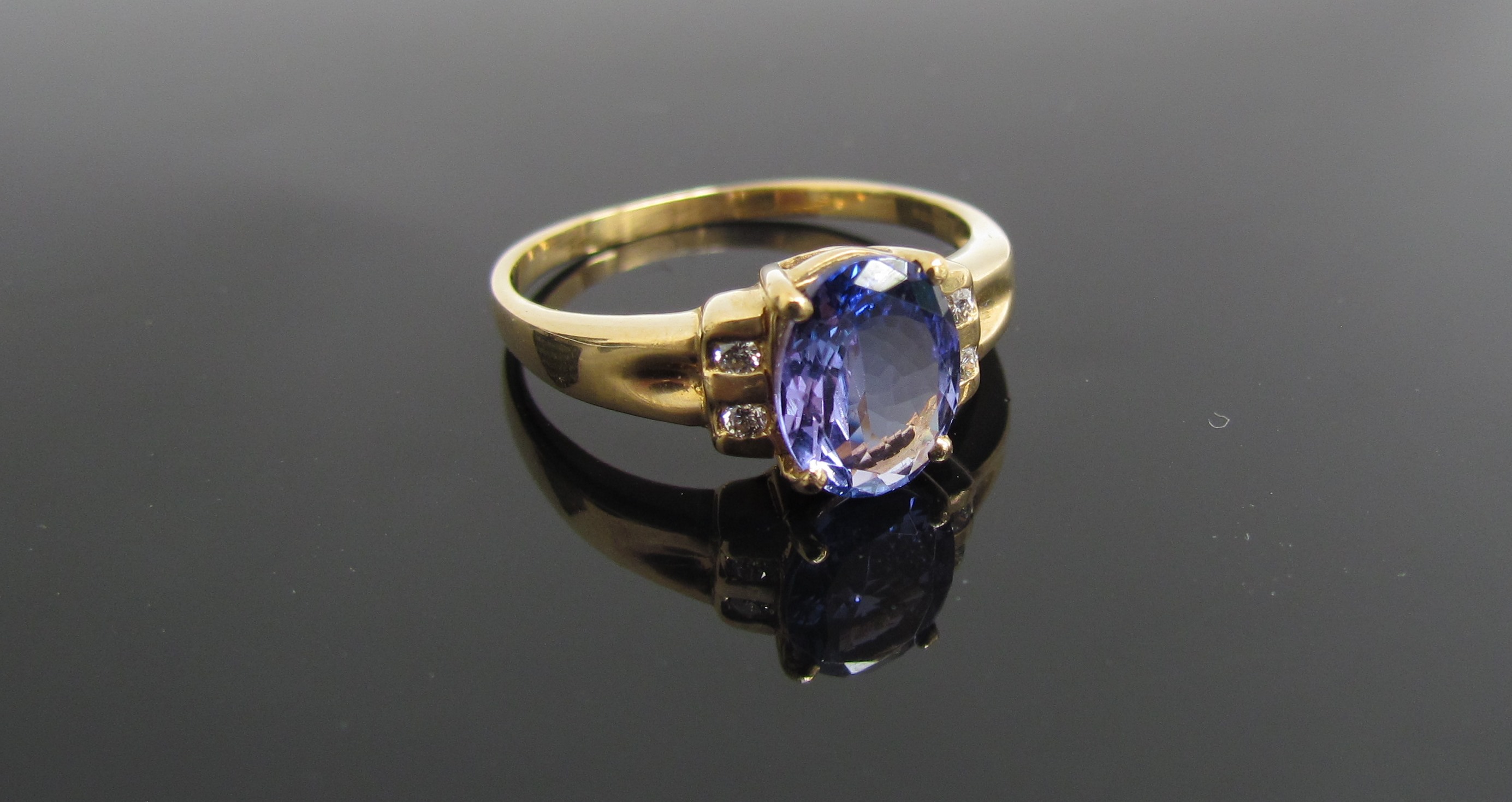 An 18ct gold tanzanite ring, the oval stone flanked by diamonds. Size R, 3.