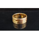 An 18ct gold textured band, 7mm wide. Size O/P, 9.