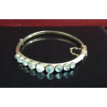 A 9ct gold stiff hinge bangle with graduated cabochon moonstones, stamped 9c, 8.