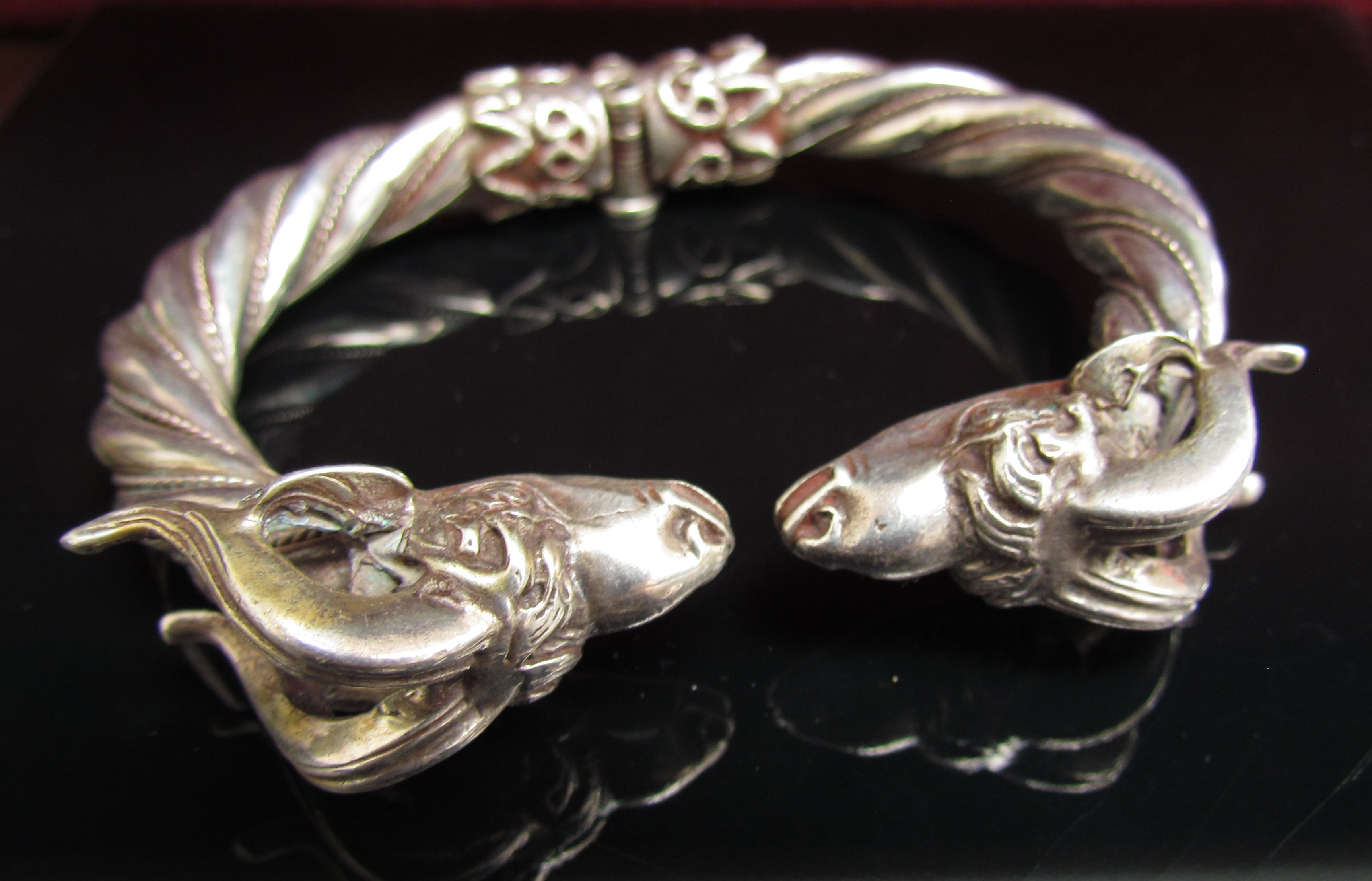 A heavy twisted white metal bangle with rams head terminals and locking hinge, stamped 900. 85.