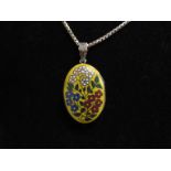 An enamelled front oval locket depicting flowers on a bright yellow ground, engraved back,