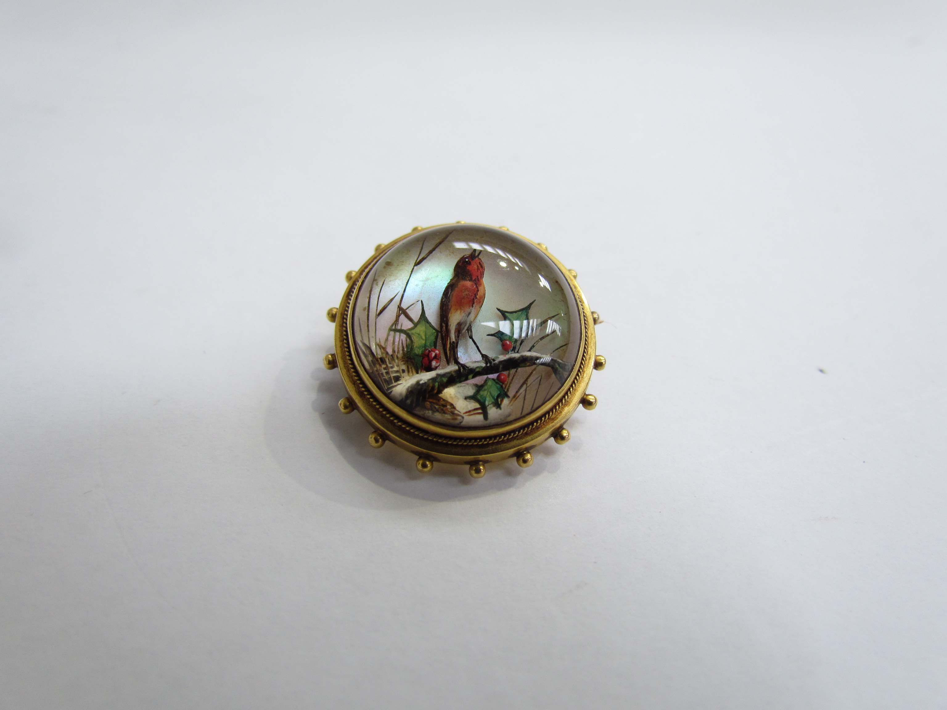 An Essex crystal domed top brooch reverse painted with image of a Robin in holly,