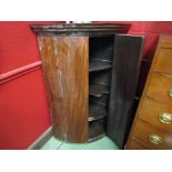A George III flame mahogany bow fronted corner cabinet, shaped central shelf,