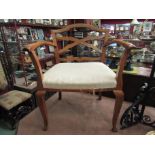 An Edwardian walnut low elbow chair with "X" frame back,