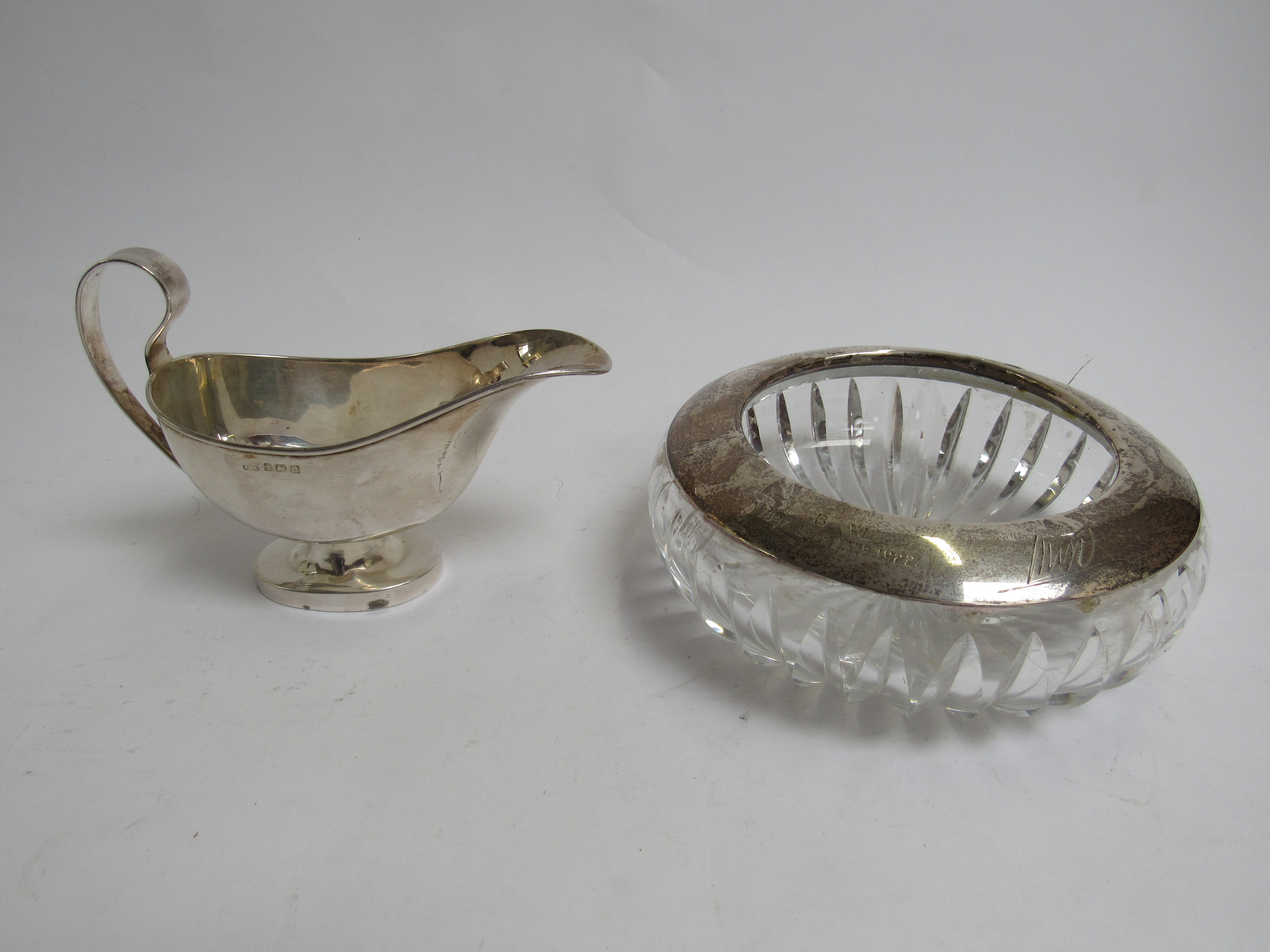 A Samuel Levi silver sauce boat (a/f) and a silver rimmed presentation ashtray, marks rubbed,