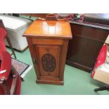 An Arts and Crafts walnut bedside cabinet with carved single door and raised back on a plinth base,