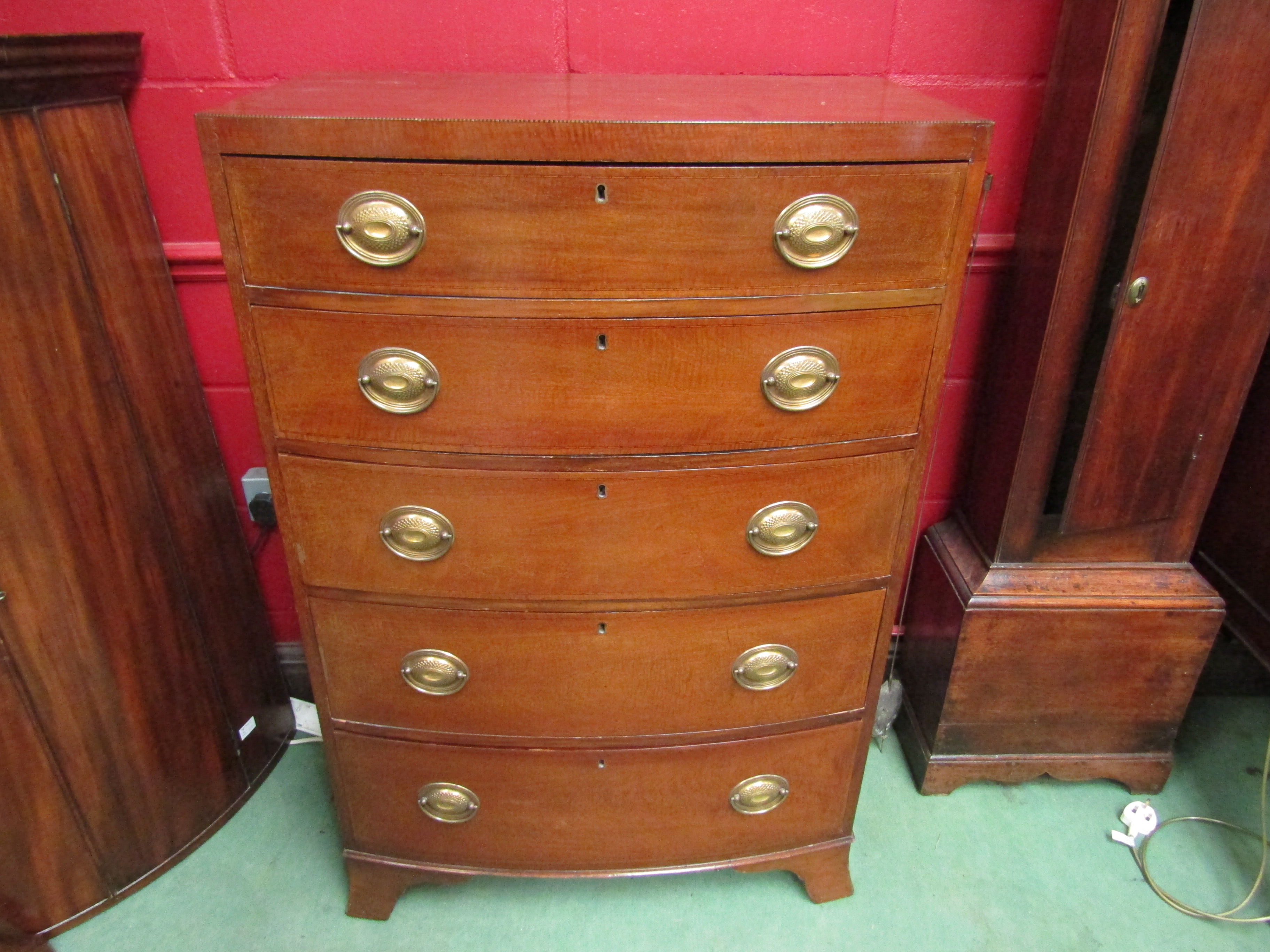 An Edwardian mahogany bow fronted chest of five straight drawers, brass oval plate handles,