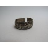 An Eastern embossed silver bangle with panels of birds and wild animals, 6cm diameter,