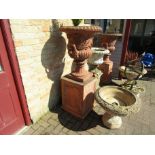 A near pair of substantial terracotta urns on plinths 130cm tall and 140cm tall