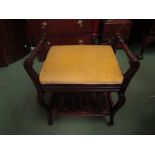 An Arts and Crafts piano stool with lift up seat and undertier