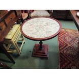 A circular mahogany side table with embroidered panel inset, banded inlay surround,