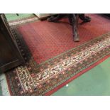 A wool rug with red ground, central square, multiple borders and tasselled ends,