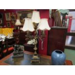 An ornate brass five sconce table electrolier with black and white square marble base on brass paw