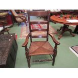 A 19th Century beech four ring ladder-back country elbow chair the rush seat over turned legs and