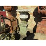 A composition urn on plinth with grape and vine decoration,