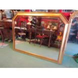 A large modern gilded wall mirror with canted corners, bevelled glass,