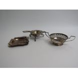 A silver ash tray, pierced twin handled dish and tea strainer with stand marked 800,